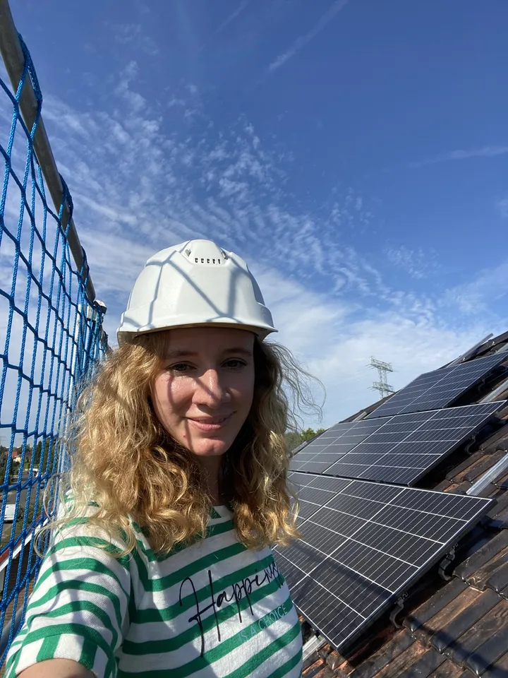 Elena Zhigalina in a hard hat on a roof with solar panels